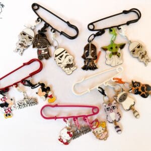 AFDE3357-E73A-49CE-B505-378A9B5DA23A Three stitch markers on a handy kilt pin.